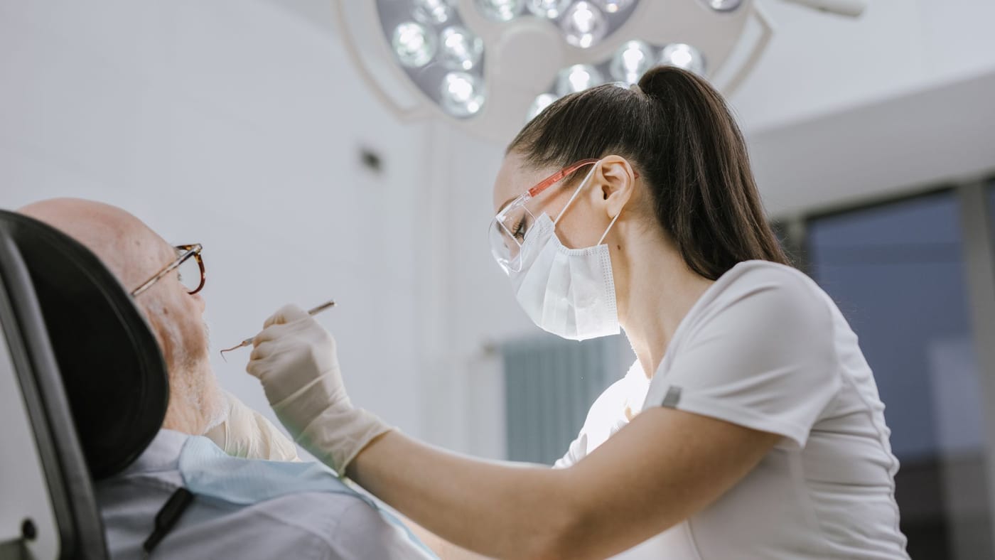 Dentista atendendo um paciente em consultório odontológico
