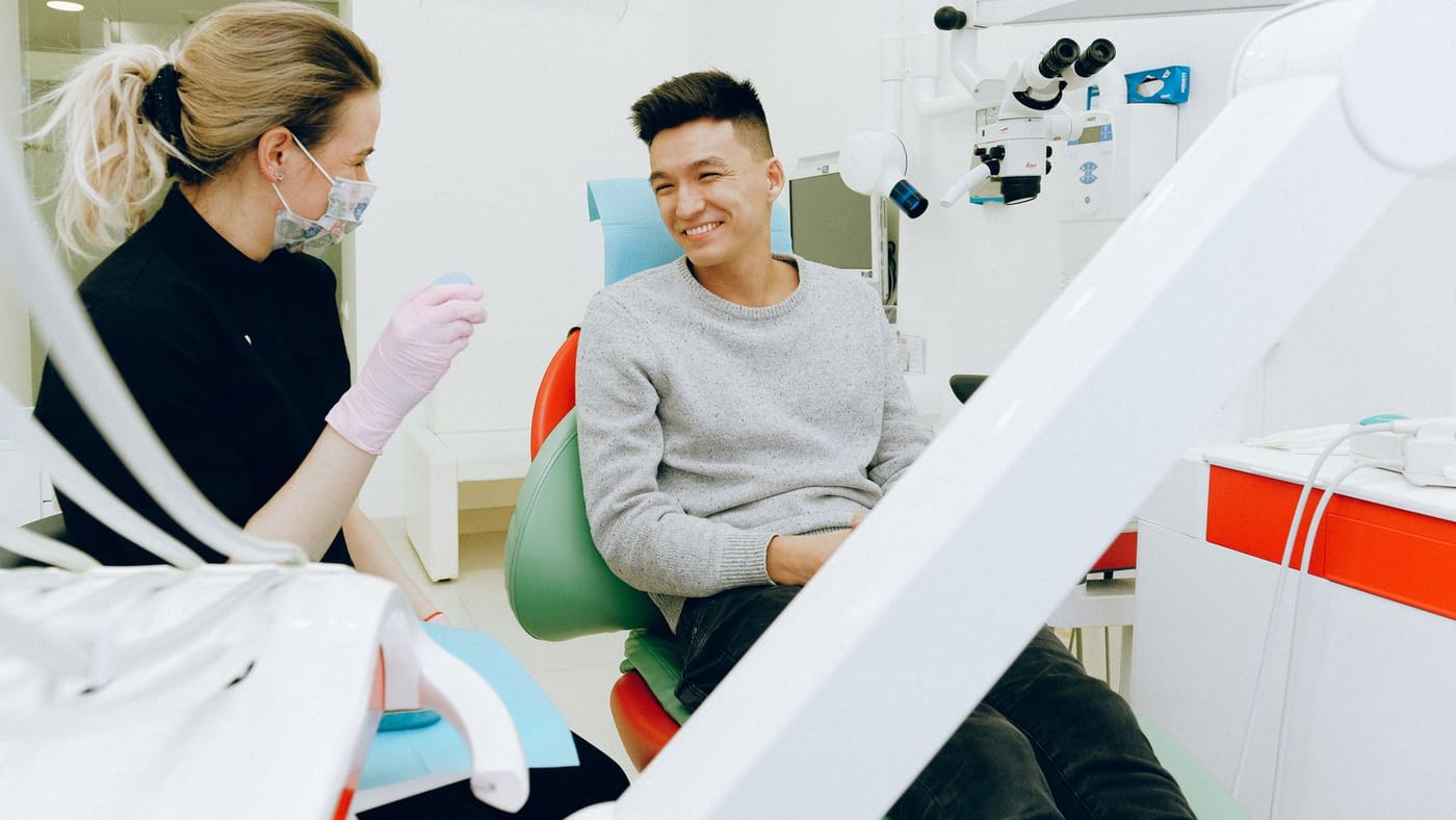 Dentista orientando o paciente na cadeira odontológica